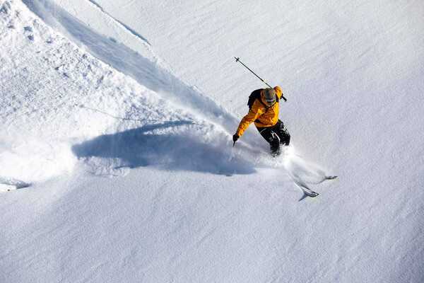 An off piste skier skiing through powder snow